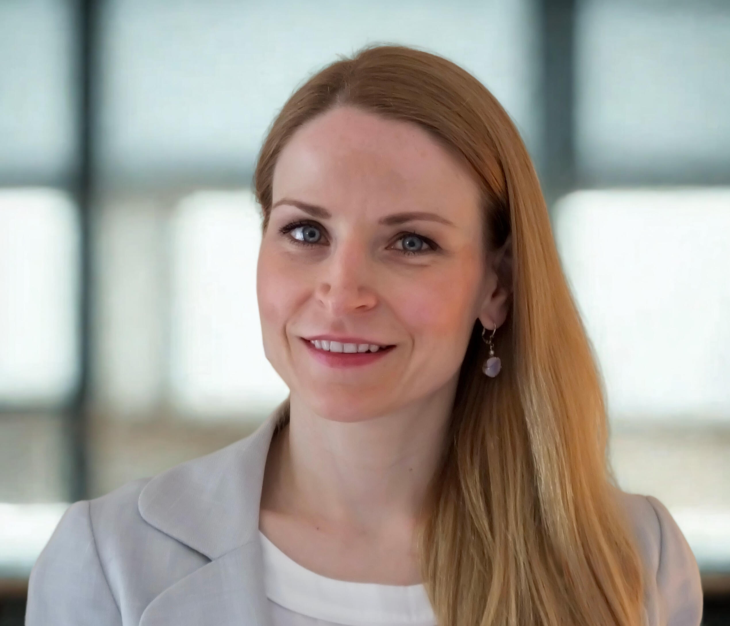 “A person in a light blazer smiling in a well-lit office.” Valley PSA - Psychological Services and Analysis